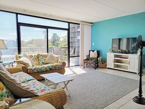 A living room with a sofa, armchair, and a television on a stand.