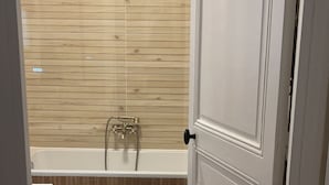 Une salle de bain avec un mur recouvert de panneaux en bois, une baignoire et une pomme de douche.