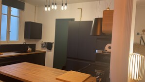 Une cuisine moderne dotée d’un plan de travail en bois, d’un four encastré et d’un luminaire suspendu.