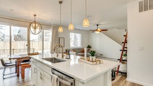 A modern kitchen with a large island, pendant lights, and a view to the outside. - Bright Colorado Springs Home, 10 Mi to Dtwn! (Colorado Springs)