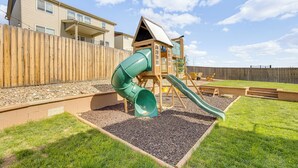 A playground with a slide and climbing area, surrounded by a wooden fence and a grassy lawn. - Bright Colorado Springs Home, 10 Mi to Dtwn! (Colorado Springs)