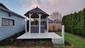 A wooden gazebo with a sloped roof, a hot tub, and a wooden deck.