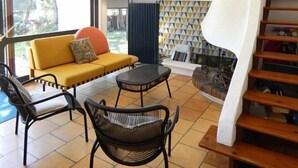 A modern living room with a sofa, chairs, a table, and a staircase. - Villa ' L'échappée Belle' (SEIGNOSSE)