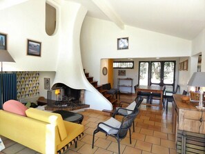 Un salón amplio con chimenea, un sofá amarillo y una mesa de comedor con sillas.