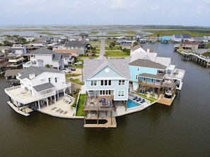 Ein Haus am Wasser mit großem Pool, einer Anlegestelle und einem Boot.