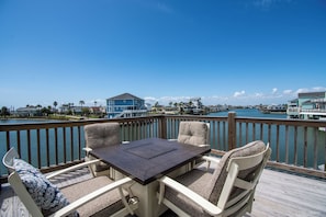 Eine Terrasse mit Tisch und Stühlen mit Blick auf eine Marina mit Booten und Häusern.
