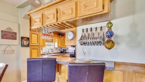 A kitchen with wooden cabinets, a clock, and hanging decorative items.