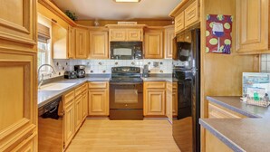 A kitchen with wooden cabinets, a stainless steel refrigerator, a microwave, and a stove.