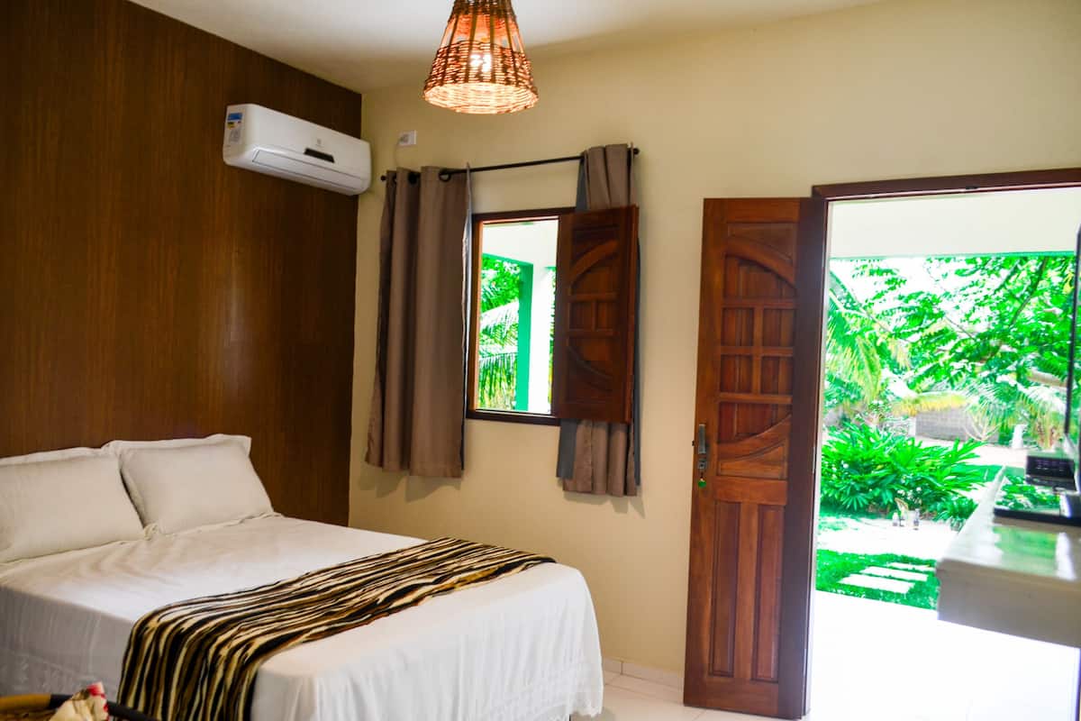 Un dormitorio con cama, equipo de aire acondicionado, ventana con cortinas y vistas al exterior.
