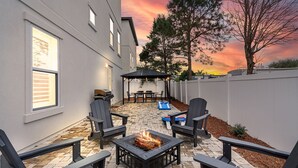 Un patio con una fogata, mobiliario exterior y vistas al atardecer.