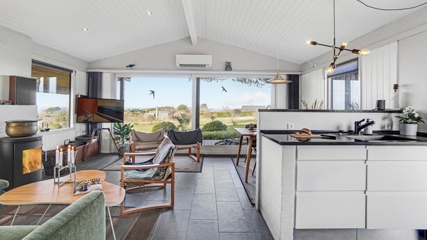 Una cocina moderna con una isla grande, un comedor con chimenea y vistas al exterior.