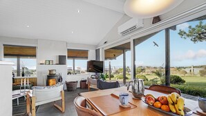 Una cocina moderna con un ventanal amplio, un comedor con una mesa dispuesta para dos personas y vistas al exterior.