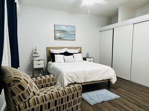 A bedroom with a bed, a nightstand, a chair, a painting, and a wardrobe. - Adorable Private Room with partial Sea View (Sentry Hill)