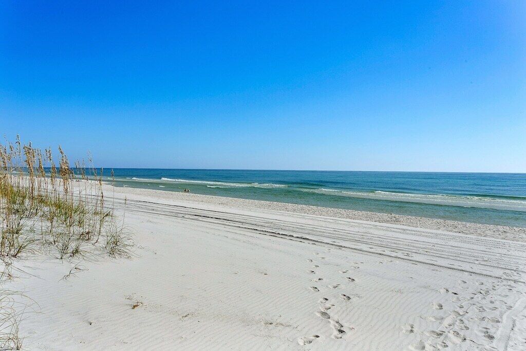 A beach with white sand and clear blue water.