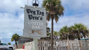 Un letrero de madera anuncia el restaurante de ostras Peg Leg Pete's, con vista a la playa.