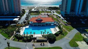 Un hotel con piscina, rodeado de vegetación y vista al océano.