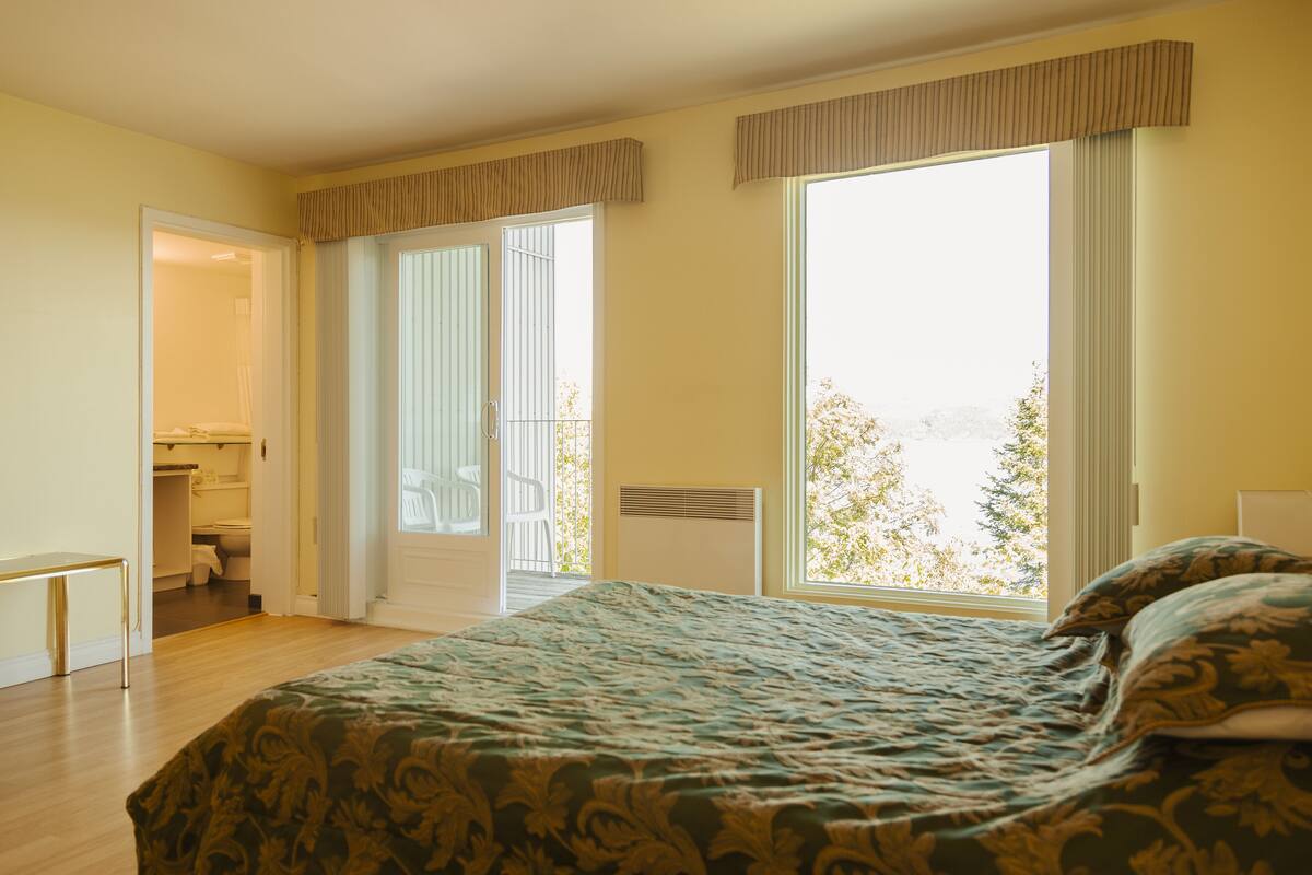 Ein Schlafzimmer mit einem großen Bett, einem Kleiderschrank und Blick ins Freie.