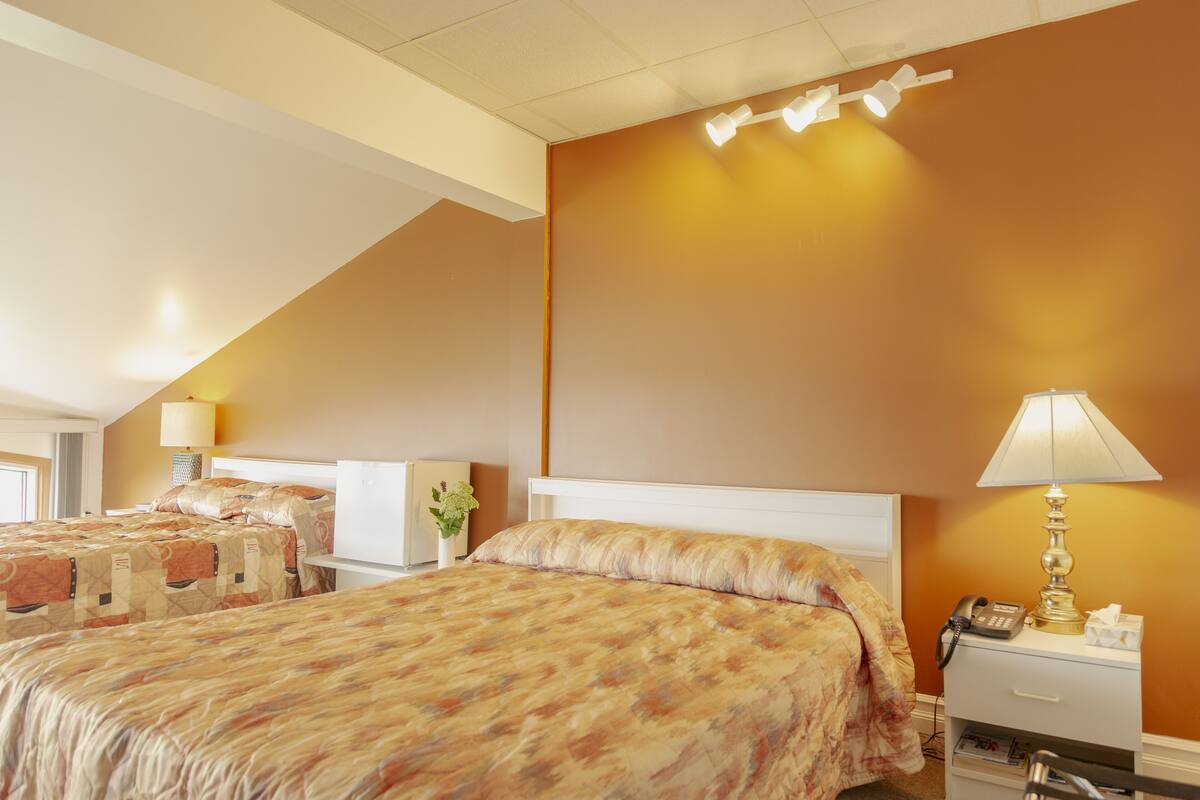 Ein Hotelzimmer mit zwei Betten, einem Nachttisch mit Lampe, einem Telefon und einer Wandleuchte.