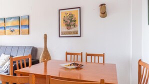 Un comedor con una mesa y sillas de madera, un cuadro enmarcado sobre la mesa y una cesta tejida en la mesa.