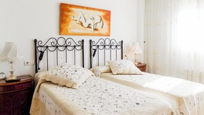 Una cama doble con ropa de cama floral, una mesita de noche con lámpara y un cuadro sobre la cama.