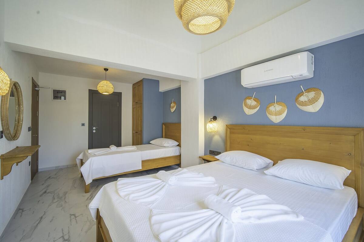 Ein Hotelzimmer mit zwei Betten, einem Holzkopfteil, einer Wand-Klimaanlage und einer Deckenleuchte.