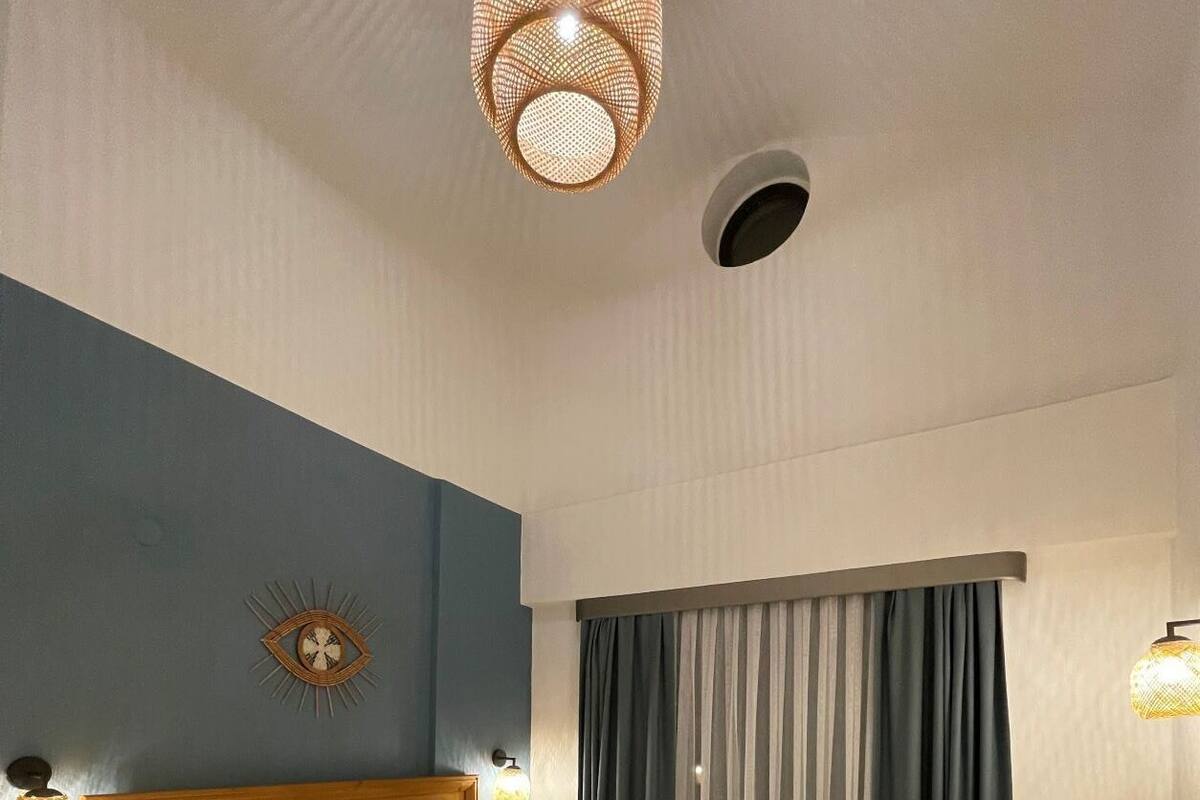 Ein modernes Hotelzimmer mit einem hölzernen Bett, einer Wanduhr und einem großen Fenster mit Vorhängen.