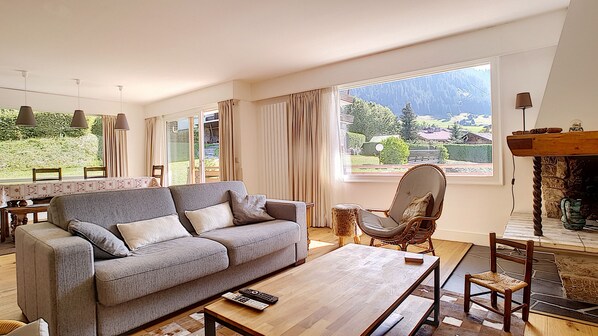 A living room with a sofa, armchairs, a coffee table, and a fireplace.