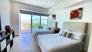 Ein Hotelzimmer mit zwei Betten, einem großen Fenster mit Blick auf die Stadt und einem Gemälde an der Wand.
