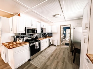 A modern kitchen with white cabinets, a stainless steel stove, and a black countertop.