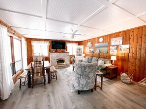 Cozy living room with a stone fireplace, comfortable sofa, and dining area.