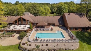 Een lodge met een zwembad, buiten zitplaatsen en een groot gebouw met meerdere daken.