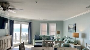 Un salon avec vue sur l’océan, un coin repas et un ventilateur de plafond.