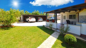 Una casa con garage, patio coperto e prato curato.