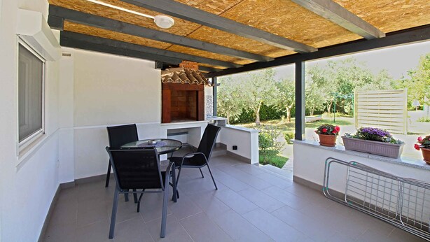 Una veranda coperta con tavolo e sedie, un camino in mattoni e piante in vaso.