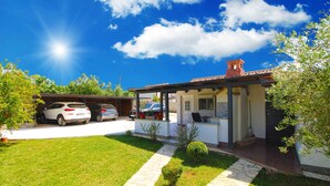 Una casa con portico coperto, un garage con auto e un prato curato.
