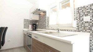 Una cucina compatta con un piano di lavoro bianco, un forno integrato e una macchina da caffè.