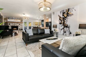 Relax in this stylish living room with a leather sofa, stone fireplace, and a large abstract painting.