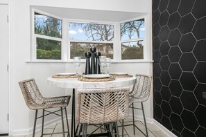 Enjoy meals in this cozy dining area with a round table for four, surrounded by wicker chairs and offering a view of the outdoors.