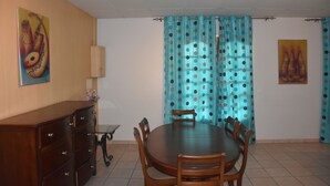 A dining area with a round table and chairs, a wooden cabinet, and a lamp. - FURNISHED HOUSE COSY (Libreville)