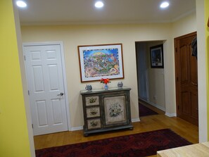 Enter a hallway with a beautifully patterned rug and a framed map of California above a decorative cabinet.