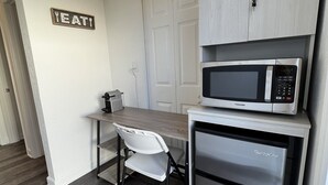 Cozinha compacta com micro-ondas, geladeira e um espaço de refeições com uma cadeira.