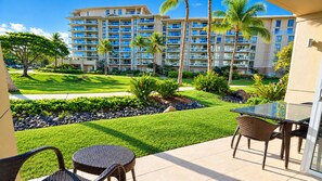 A hotel balcony with a view of a well-maintained lawn, palm trees, and a multi-story building in the background.