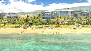 Un hôtel en bord de mer composé de plusieurs bâtiments, doté d’une plage de sable et bordé de palmiers.