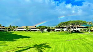 Ein Hotel mit mehreren Gebäuden, einem gepflegten Rasen und einem deutlich sichtbaren Regenbogen.