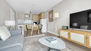 Un apartament modern amb saló, menjador, cuina i un televisor gran.