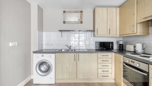 Una cuina moderna amb rentadora, microones, torradora i forn.