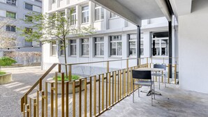 Moderni rakennus, jossa on parveke, ulkotila istumista varten ja portaikko.