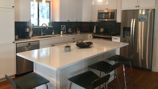A modern kitchen with white cabinetry, stainless steel appliances, and a central island with bar stools. - Walk to the crystal clear San Marcos river (San Marcos)