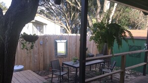 A wooden deck with a table and chairs, surrounded by a wooden fence and a green wall. - Walk to the crystal clear San Marcos river (San Marcos)