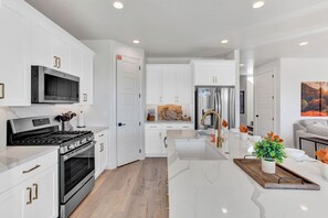 Una cocina moderna con armarios blancos, electrodomésticos de acero inoxidable y encimera de mármol.
